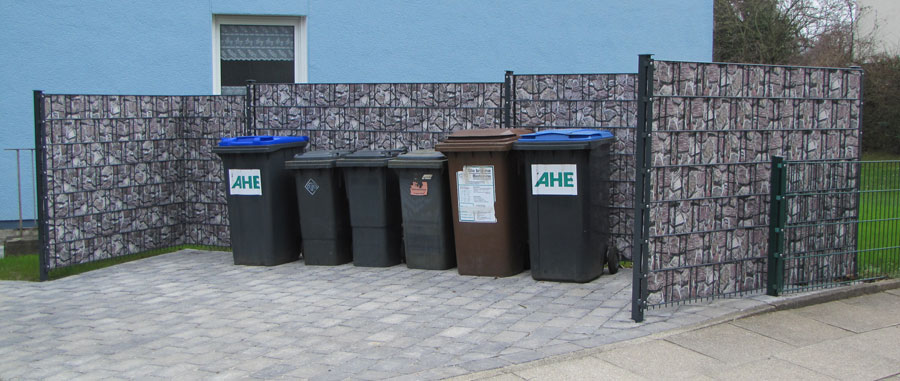 Mülltonnen hinter modernem Sichtschutzzaun im Hof