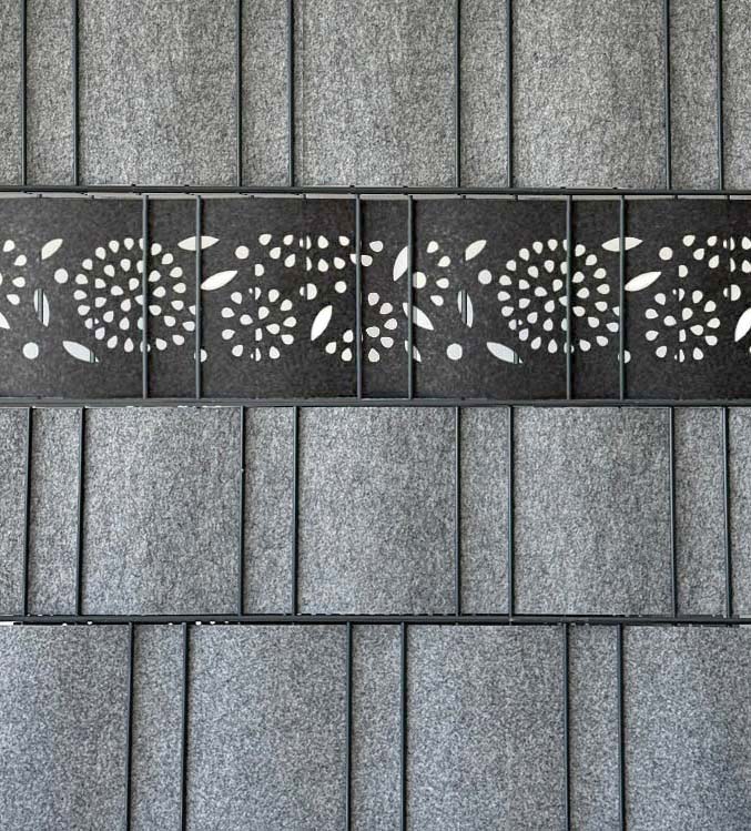 Detailansicht graues Akustik Wandpaneel aus Filz mit mittlerer schwarzer Reihe und ausgestanztem Blumenmuster