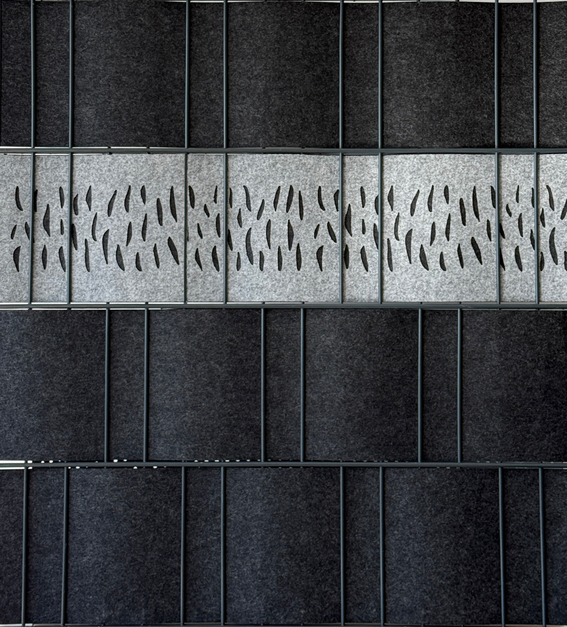 Detailaufnahme grauer Akustik-Wandverkleidung aus Filz mit perforierten Designpaneelen für Schallabsorption